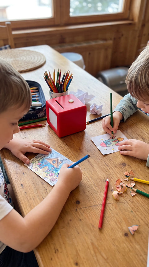Zwei Kinder malen gemeinsam eigene Motive aus, neben ihnen steht Fantasini.